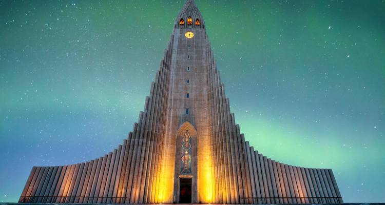 Structure d'église spectaculaire éclairée la nuit avec des aurores boréales au-dessus.