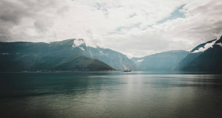Fjord landscape with cloudy skies and mountains.