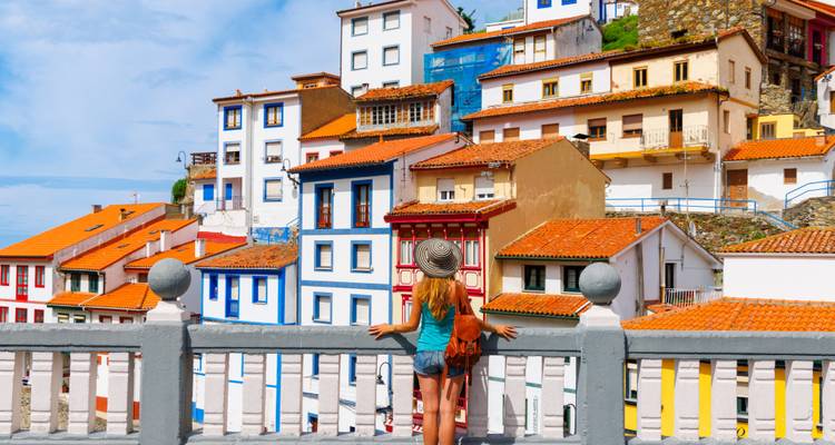 A woman admiring colorful houses from a balcony.