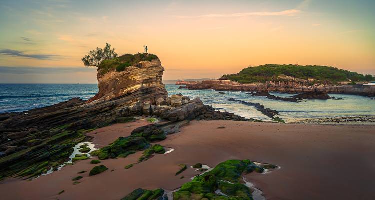 Scenic coastal rock formation with the ocean at sunset.