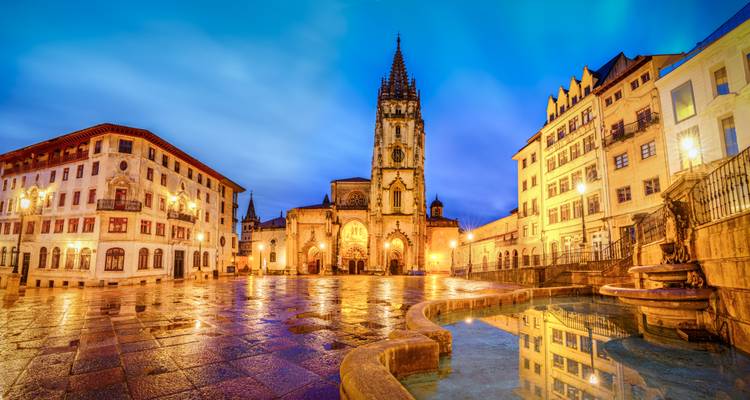 A cathedral in a vibrant plaza lit up at dusk.