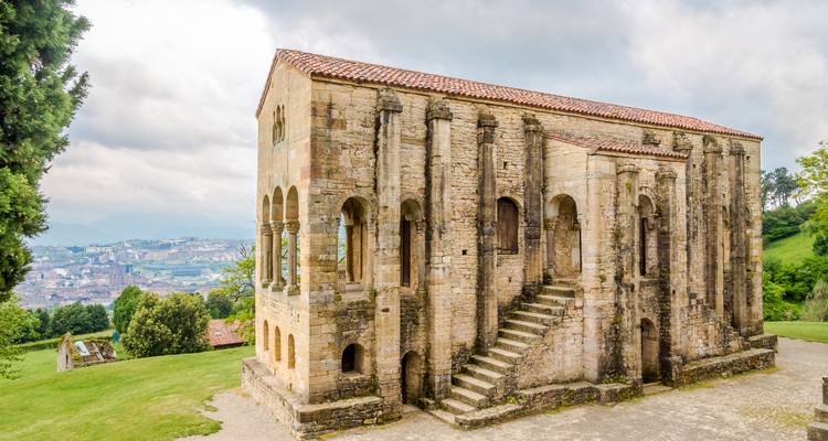 A historic building featuring Romanesque architecture with the city in the distance.