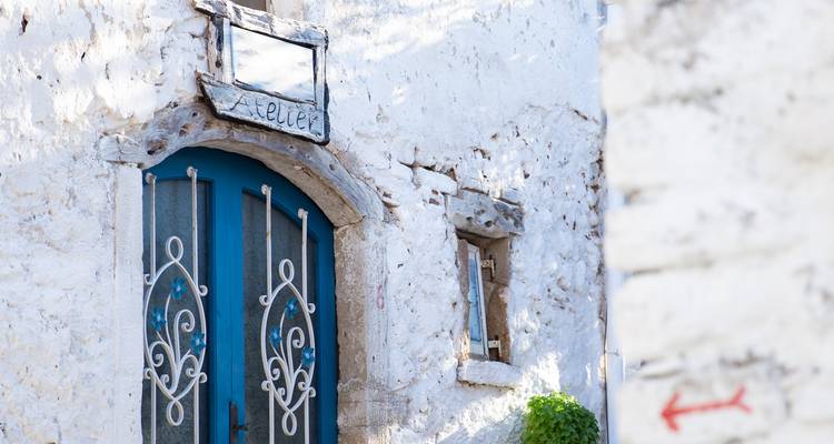 Gros plan d'une porte blanche rustique avec une grille métallique décorative.