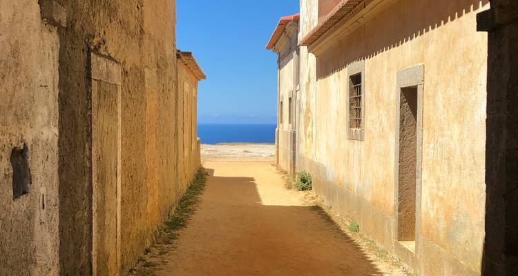 Ruelle entre de vieux bâtiments menant à une vue sur l'océan.