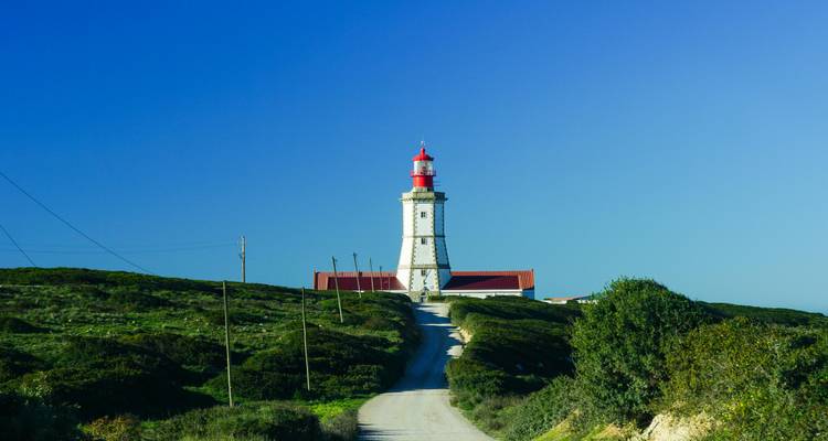 Phare sur une colline avec un ciel bleu clair.