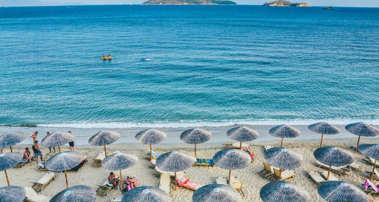 Beach with sun umbrellas and distant islands.