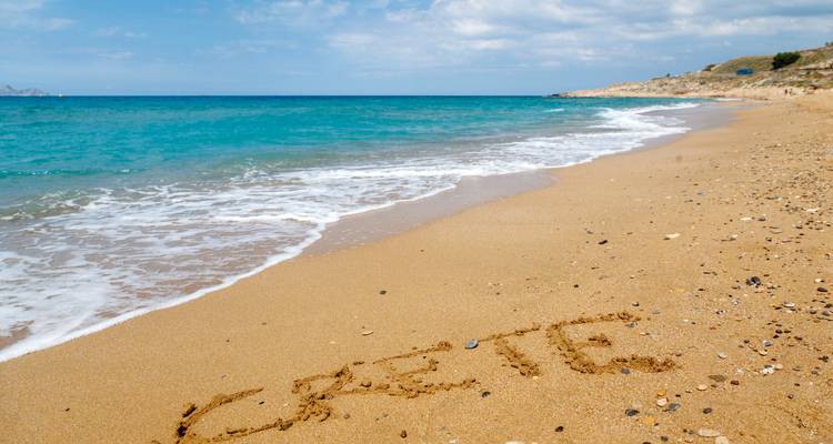 Sandy beach with the word 'Crete' written in the sand.