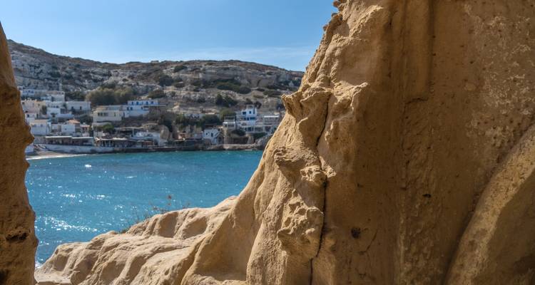 Rocky shoreline with blue sea and distant buildings.