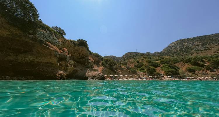 Vista costera desde el agua con sombrillas en la playa.