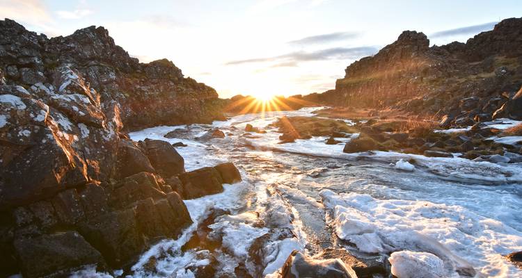 River flowing through a rocky landscape with sunburst.