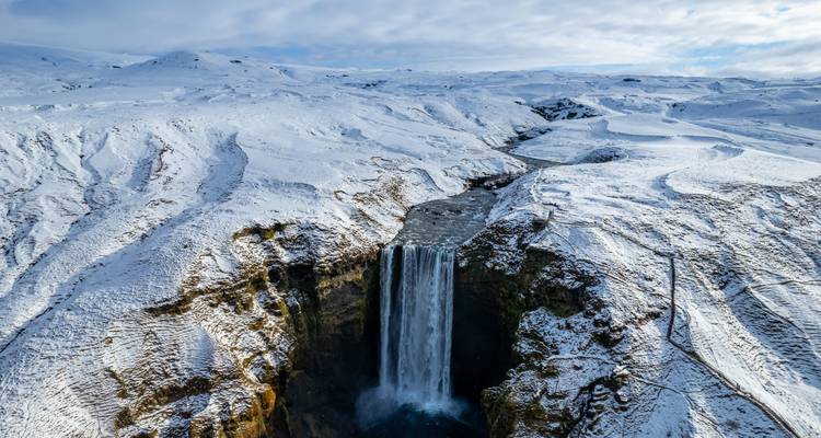 A stunning waterfall surrounded by snow-covered landscape.