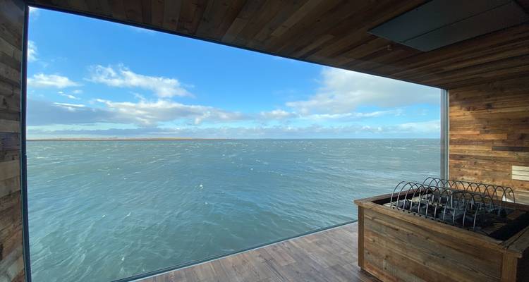 Indoor view of water and sky through large windows.