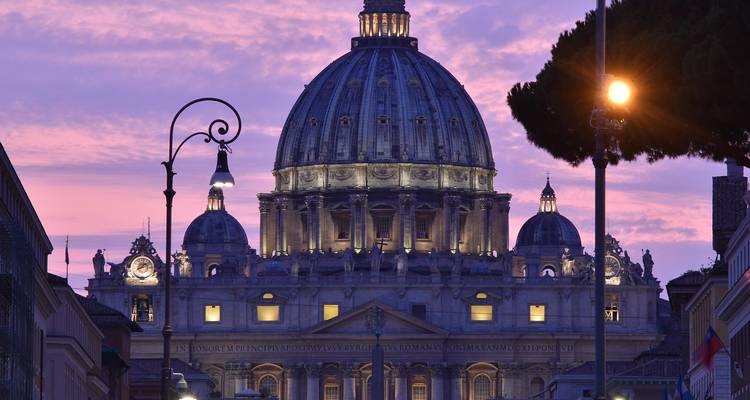 Dôme illuminé d'une cathédrale contre un ciel violet au crépuscule.