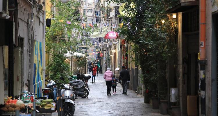 Rue pavée étroite avec des gens et des décorations colorées.