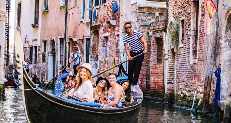 Grupo disfrutando de un icónico paseo en góndola a través de los estrechos canales bordeados de ladrillo de Venecia.