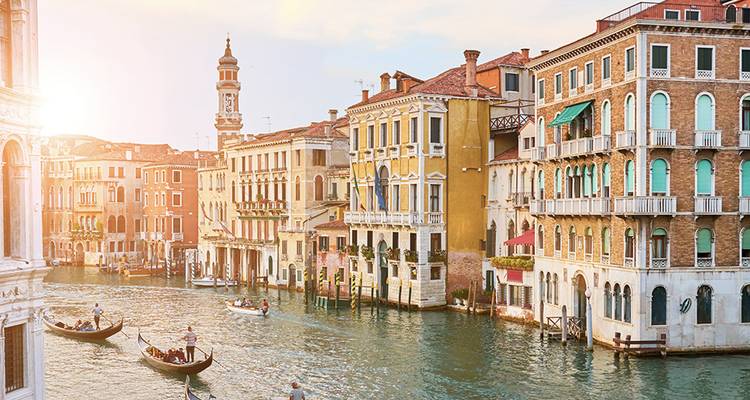 Goldenes Sonnenlicht beleuchtet Gondeln und elegante Paläste entlang des Canal Grande in Venedig
