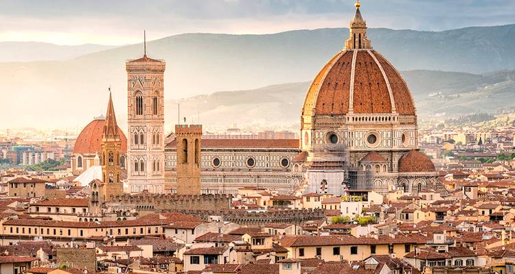Panoramisch uitzicht op de Duomo van Florence en Giotto's Campanile die oprijzen boven terracotta daken bij zonsopgang.