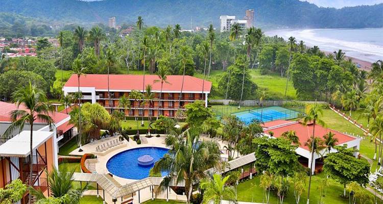 Resort con piscina y cancha de tenis cerca de una playa.