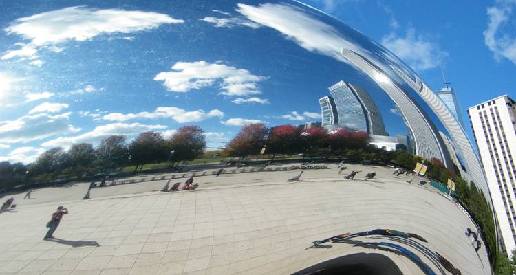Reflet dans une sculpture montrant l'horizon urbain et le ciel bleu.