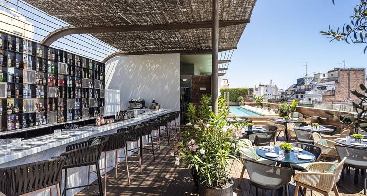 Bar avec espace repas et piscine sur une terrasse de toit surplombant la ville.