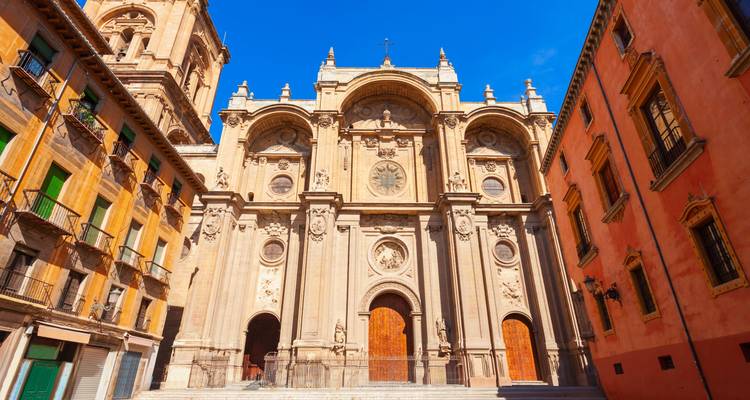 Frontansicht der Kathedrale von Granada, flankiert von farbenfrohen Gebäuden.