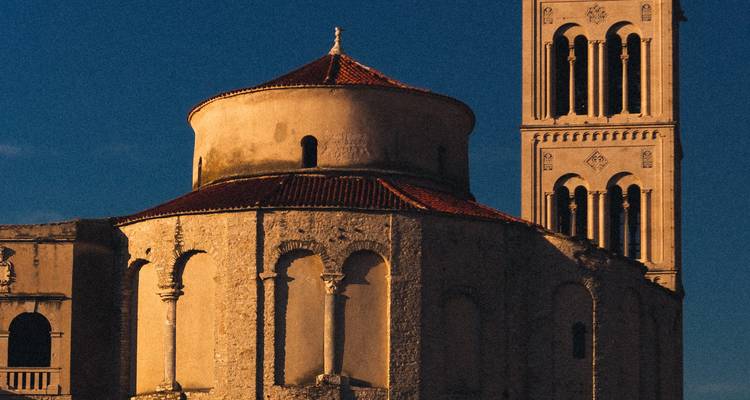 Vieille église de pierre avec une tour ronde au coucher du soleil