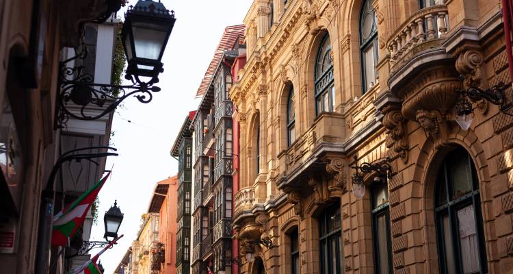 Architektonisch reiche Straße in Bilbao mit dekorativen Fassaden und Flaggen.