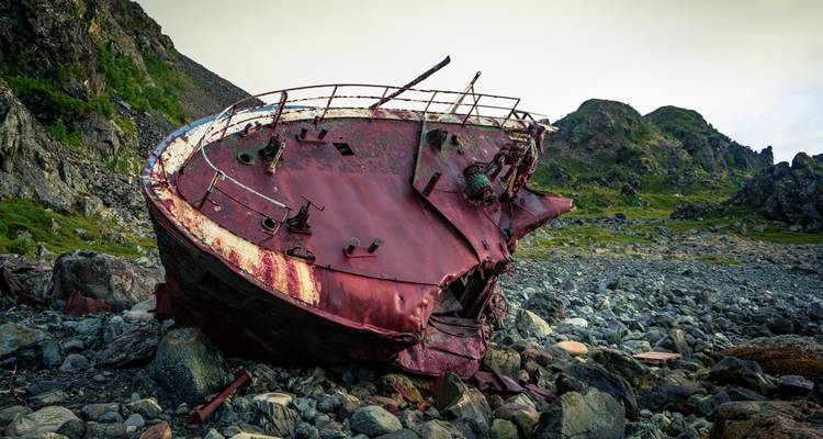 Épave de navire abandonné sur terrain rocheux.