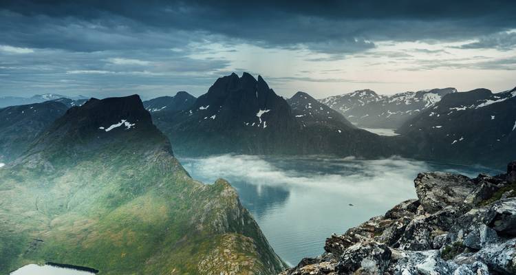 Vue de vallée brumeuse avec montagnes couvertes de forêt.
