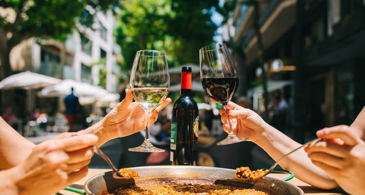 People enjoying food and wine at an outdoor cafe.