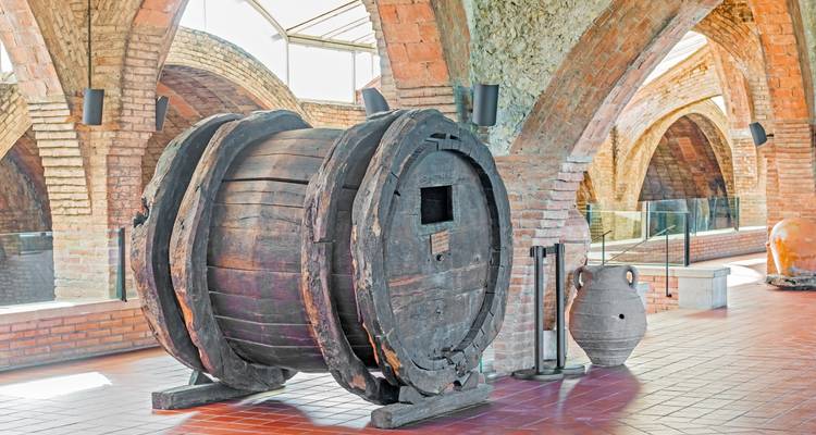 Old wooden barrel in a brick-walled cellar.