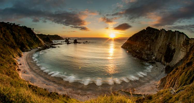 Plage magnifique au coucher du soleil avec vue sur des falaises rocheuses.