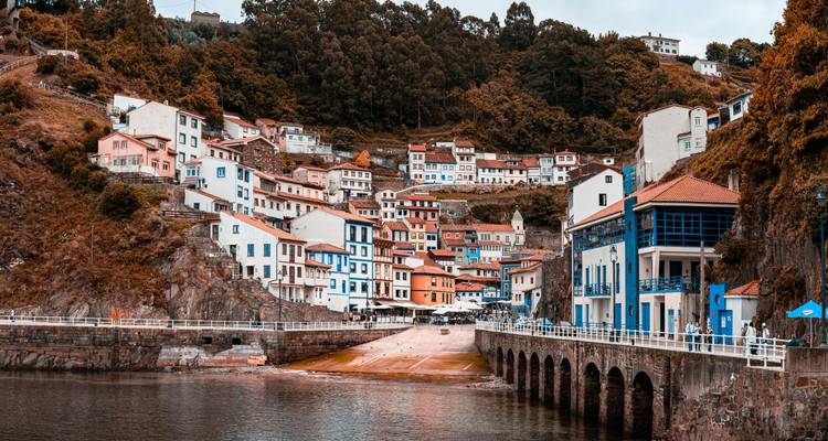 Ville pittoresque avec des bâtiments colorés à flanc de colline au bord d'une rivière.