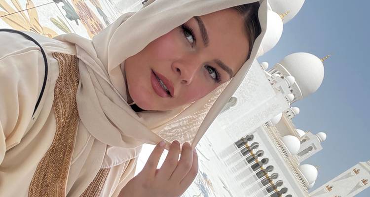 Personne en tenue traditionnelle debout près de la Grande Mosquée Sheikh Zayed.