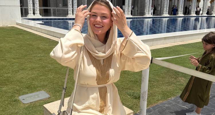 Personne souriante assise à côté d'un bassin réfléchissant.