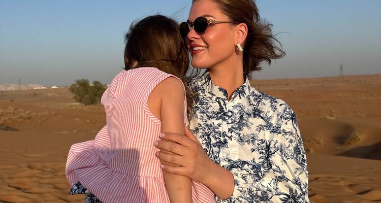 Personne tenant un enfant dans un paysage désertique.