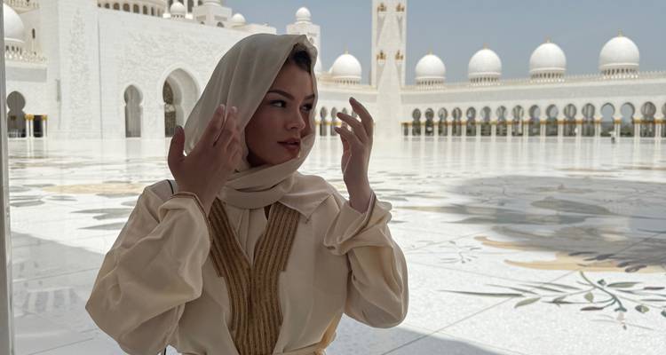 Personne en tenue traditionnelle posant à la Grande Mosquée Sheikh Zayed.