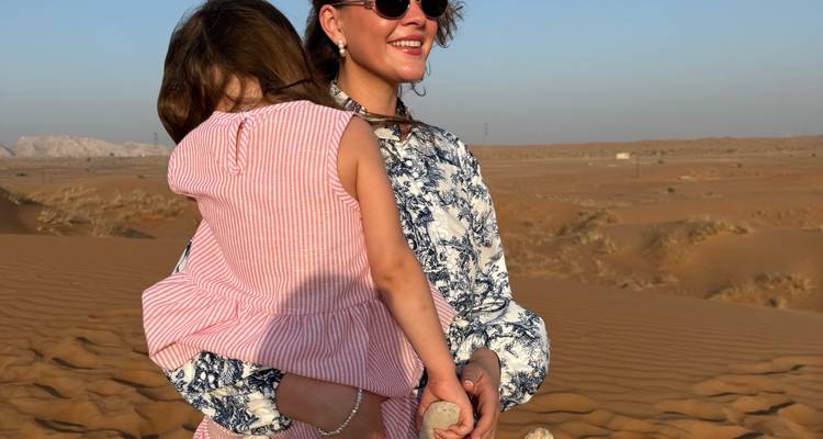 Personne tenant un enfant dans un vaste paysage désertique.