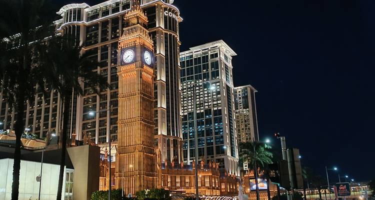 Replicated Big Ben in front of luxury hotel in Macau, illuminated at night.