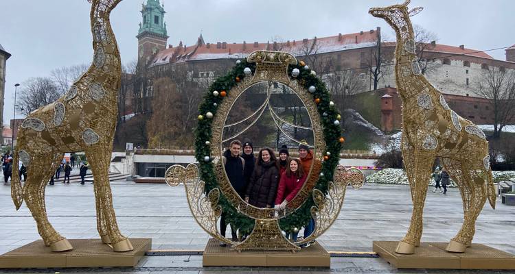 Groupe de personnes posant avec des décorations de Noël devant le château de Wawel.