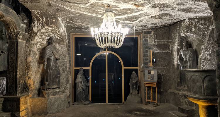 A decorated underground chapel with sculptures and chandeliers.