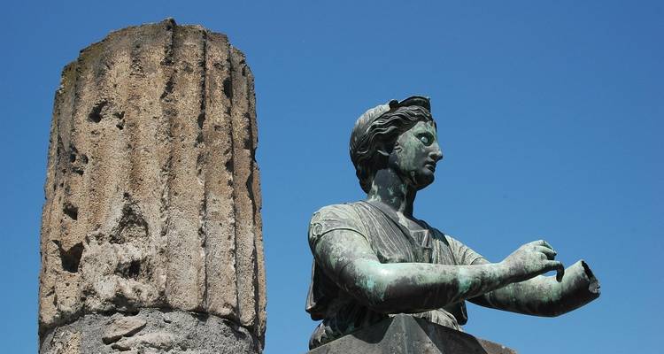 Une statue et une colonne antique contre un ciel dégagé.
