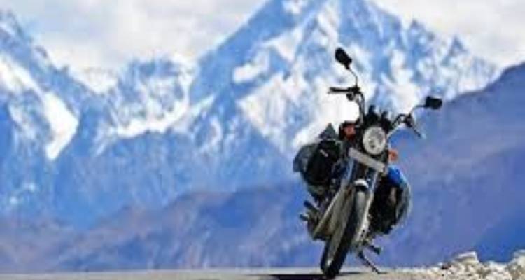 A motorcycle parked on a road with snow-capped mountains in the background.