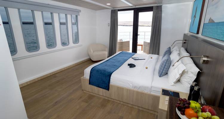Hotel room with sea view and fruits on a table.