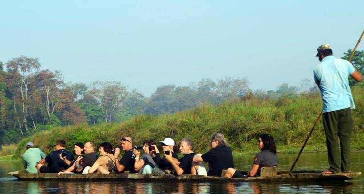 Personas disfrutando de un paseo en canoa por un río tranquilo con orillas cubiertas de hierba.