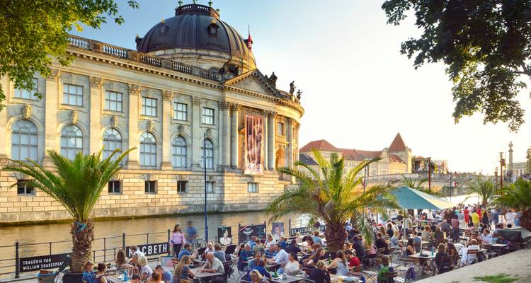 Une place active au bord d'une rivière, bondée de monde.