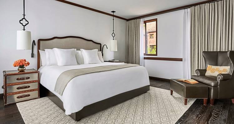 Intérieur d'une chambre d'hôtel moderne avec un lit double et des sièges confortables.