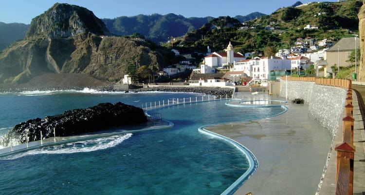 Village côtier avec une piscine naturelle et des falaises spectaculaires.