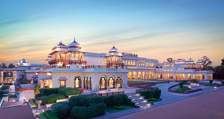 Luxuriöses palastähnliches Gebäude unter einem lebendigen Sonnenuntergangshimmel mit gepflegten Gärten.