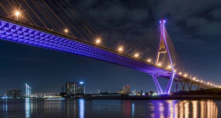 Pont illuminé la nuit se reflétant sur l'eau calme.